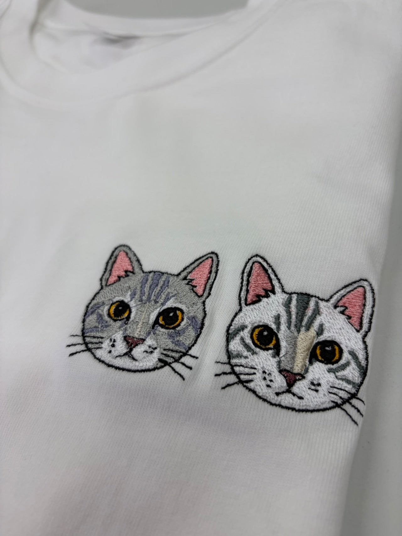 猫２匹のペット刺繍をTシャツの胸元にしている様子の写真